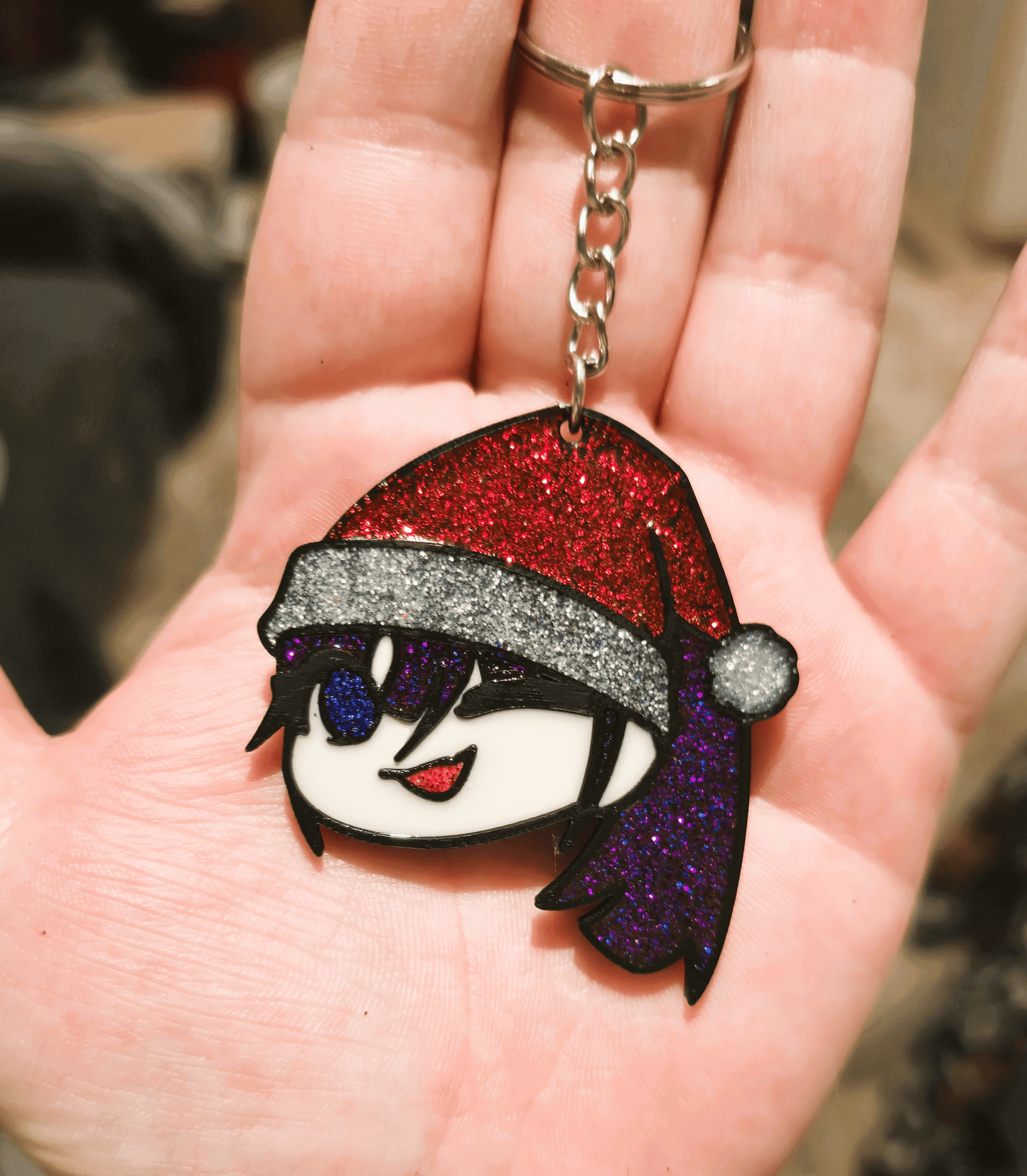 Porte-clé de collection de Naima (Ado/Usseewa) en édition Noël. Fabriqué en PLA+ par impression 3D avec ajout de résine époxy pailletée pour un effet brillant.